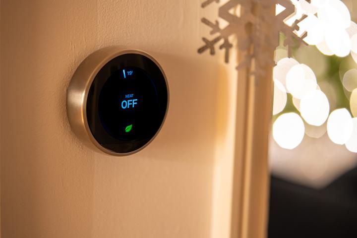 Smart thermostat with snowflake decorations hanging around it.