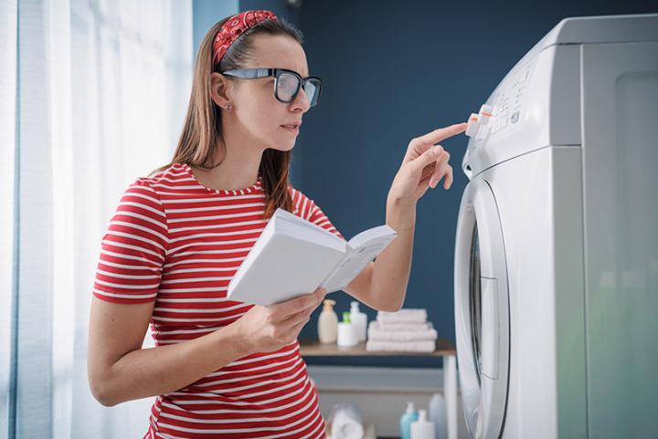 Woman reading manual for washing machine