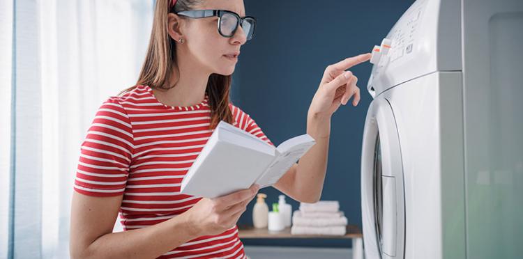 Woman reading manual for washing machine